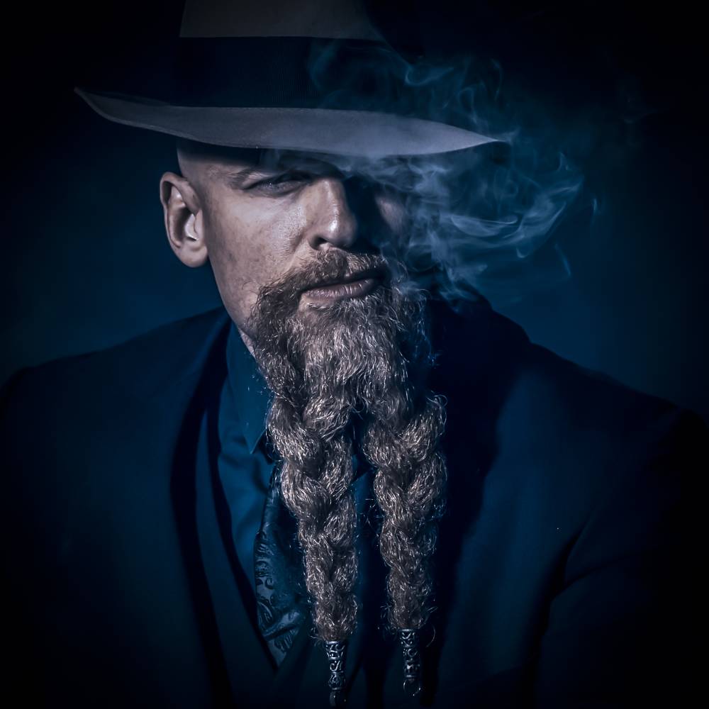 Lopes Artistiek portret van bebaarde man met hoed in blauw licht met rookeffect - professionele studiofotografie met cinematische sfeer en dramatische belichting. Artistic portrait of bearded man with hat in blue light with smoke effect - professional studio photography with cinematic atmosphere and dramatic lighting.